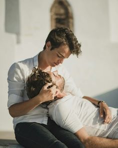 a man is sitting on the ground and hugging his woman's head with both hands