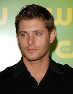 a close up of a person wearing a black shirt and looking at the camera with a serious look on his face