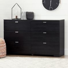 a black dresser sitting in a living room next to a clock