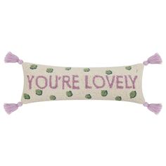 a pillow with the words you're lovely printed on it and tassels