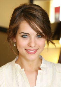 a close up of a person wearing a white shirt and smiling at the camera with blue eyes