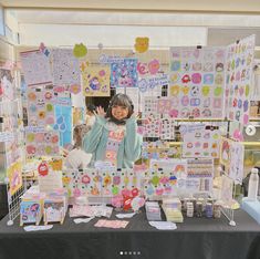 a woman standing in front of a table filled with cards and magnets on it