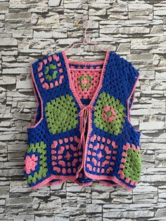 a crocheted sweater hanging on a stone wall