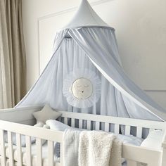 a white crib with a blue canopy over it and pillows on the bottom bed