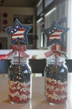 two mason jars with red, white and blue decorations in them sitting on a table