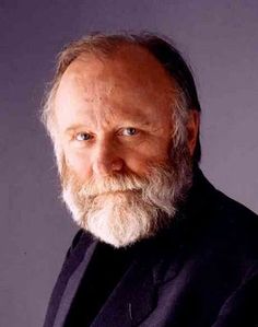 an older man with a white beard wearing a black suit