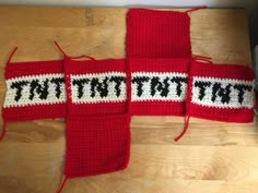 there is a crocheted red scarf with black letters on it that says, tattered