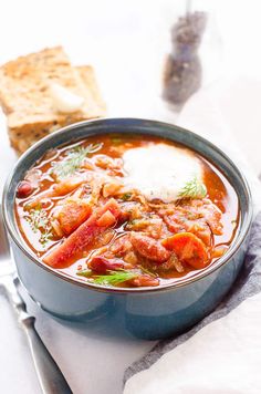 there is a bowl of soup with meat and bread on the table next to it