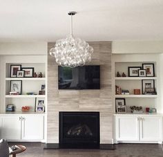 a living room with a fire place, shelves and a television mounted on the wall