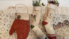 two christmas mittens sitting on top of a lace tablecloth covered bed next to each other