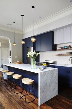 an instagramted photo of a kitchen with blue cabinets and white countertops, along with stools