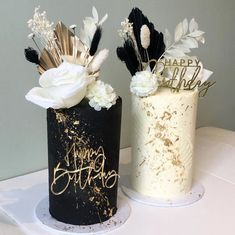 two black and white birthday cakes with flowers on each one are sitting on a table