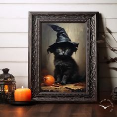 a black cat wearing a witches hat sitting in front of a framed photo with a candle