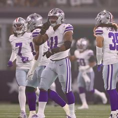 three football players standing on the field during a game with one holding his fist up