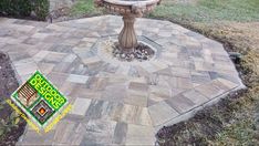 a bird bath sitting on top of a stone patio in the middle of a yard