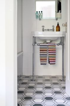 a bathroom with a sink, mirror and towel rack on the door way to another room