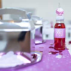 a pink table topped with a bottle of liquid