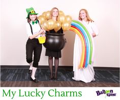 three women standing next to each other with balloons in the shape of a pot and rainbow