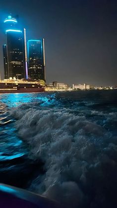 the city lights shine brightly in the night sky as boat speeds through the water on its way to shore