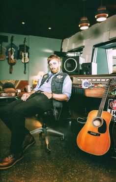 a man sitting in a chair with an acoustic guitar