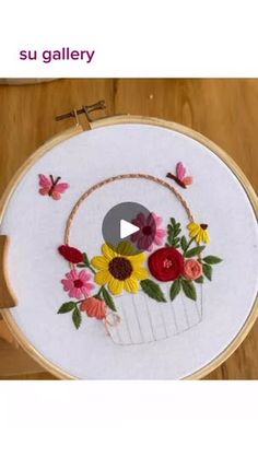 the embroidery is being worked on by someone using scissors and thread to make it look like they are holding flowers