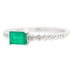 an emerald and diamond ring on a white background