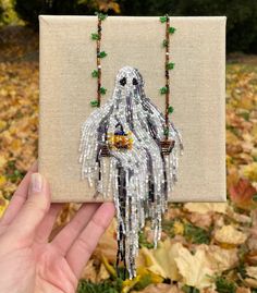 a hand holding up a small beaded ghost