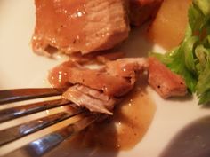 a white plate topped with meat and veggies next to a knife and fork