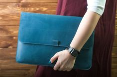 a woman holding a blue leather bag on her arm and wearing a watch around her wrist