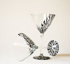 two wine glasses sitting next to each other on a white surface with zebra print designs