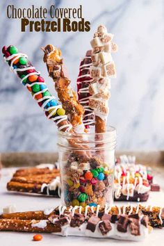 chocolate covered pretzel rods in a jar filled with candy and marshmallows