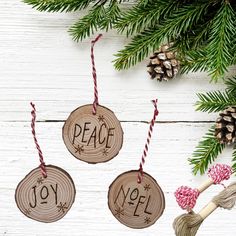 three wooden ornaments with the words peace and joy hanging from twine on a white wood background