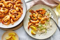 two plates with shrimp, rice and lemon wedges