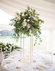 there is a tall vase with white flowers on top of the table at this wedding reception