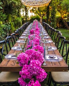 a long table set with purple flowers and place settings for an outdoor dinner party in the garden