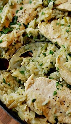 a skillet filled with chicken and rice on top of a wooden table