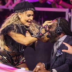 a woman with headphones on singing to a man in a suit and tie at a concert