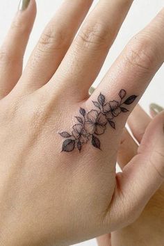 a woman's hand with a flower tattoo on the left side of her ring