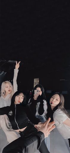 group of young women posing for the camera with their arms in the air and one woman holding up her cell phone