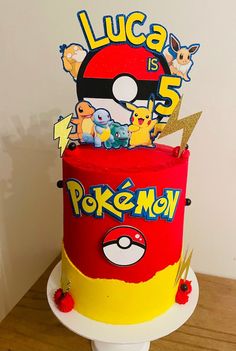 a red and yellow cake with pokemon characters on it's top, sitting on a table