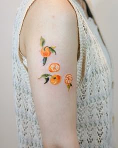 an orange tattoo on the left upper arm and right lower arm, with three oranges painted on it