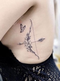 a woman's stomach with a bow and flowers tattoo on her lower back side