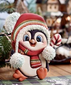 a penguin figurine wearing a red hat and scarf with a candy cane in its hand