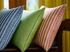 three pillows sitting on top of a wooden bench