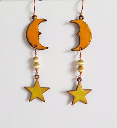 "I make these celestial copper enameled earrings by torch firing powdered glass (enamel) onto a copper crescent moon shape and copper star shape. They are made with yellow enamel and orange enamel. The moon is 3/4\" long x 3/8\" wide and the star is 1/2\" x 1/2\". The moon and star shape are attached with copper wire and colored glass beads. The ear wire is hypo allergenic. Total length with hook is about 2 1/2\" long. These earrings are fun and unique, and very light weight and comfortable to w Handmade Yellow Star-shaped Jewelry, Handmade Yellow Star Jewelry, Torch Fired Enamel Jewelry, Star Dangle Earrings, Crescent Moon And Star, Enamel Stud Earrings, Celestial Earrings, Rustic Earrings, Painted Jewelry