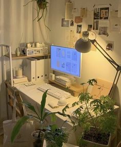 a desk with a computer and plants on it