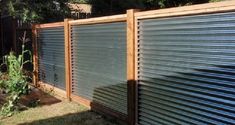 a fence that is made out of metal sheets and wood slats, in the backyard