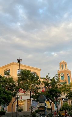 a clock tower in the middle of a park with trees and people sitting on benches