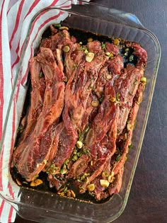 a glass casserole dish filled with meat and pistachios on a table