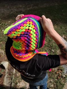 a man holding up a multicolored crocheted hat